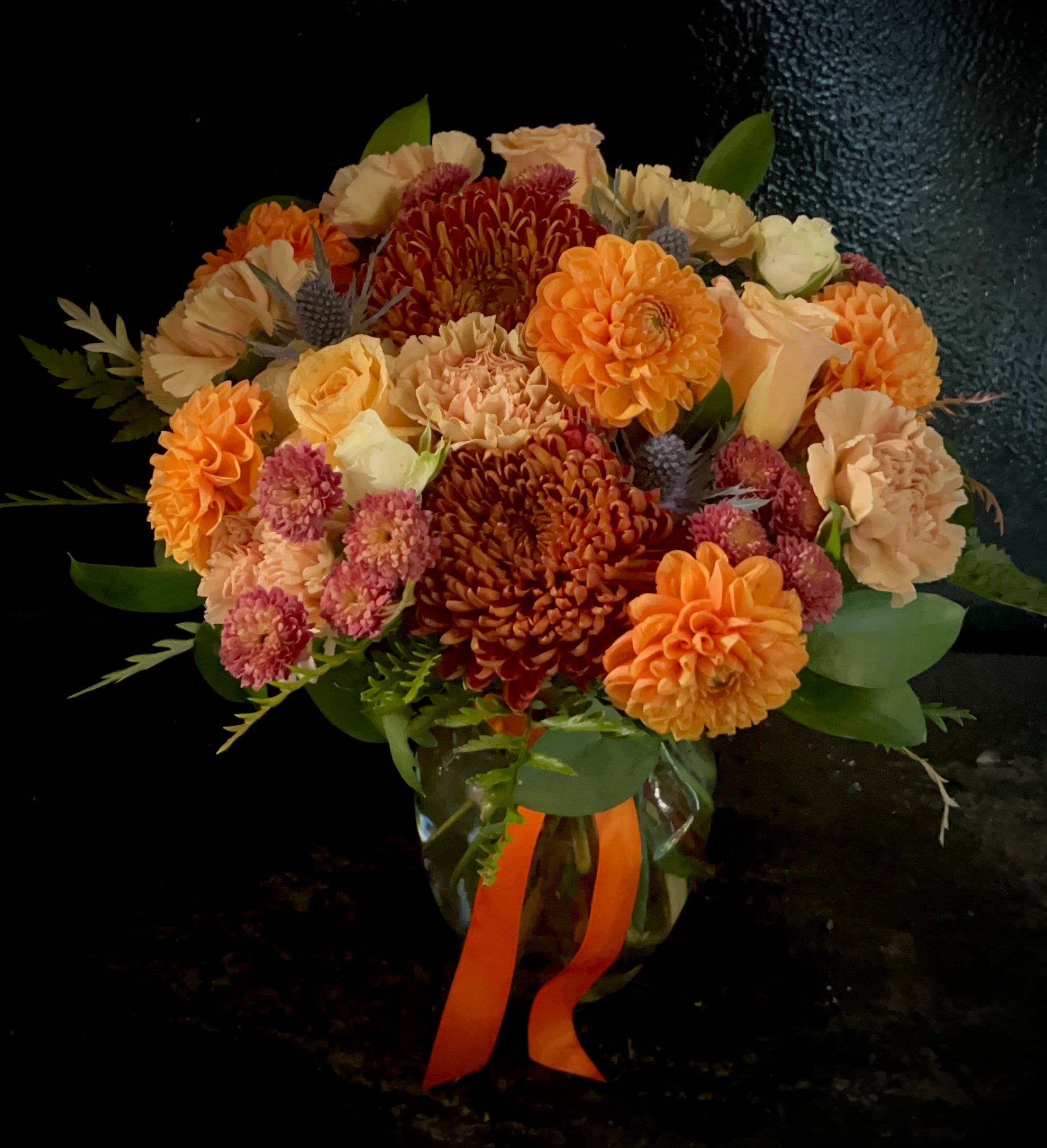 Moderate sized vase arrangement with autumn toned mixed blooms.
