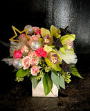Pink blooms with green cymbidium orchids tucked in a box with sparkly star embellishments for a magical vibe.