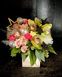 Pink blooms with green cymbidium orchids tucked in a box with sparkly star embellishments for a magical vibe.