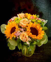 Roses and sunflowers with seasonal filler, accent flowers mixed arranged in a vase. 