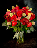 Mix of red premium blooms in a vase with mixed greens.
