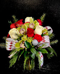 Holiday vase arrangement with designer's selection of blooms and embellishments for a festive vibe.