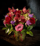 Mixed vase arrangement with roses, cymbidium orchids, seasonal blooms and mixed greens