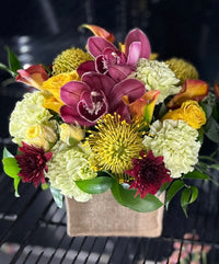 Mixed blooms and tropical flowers in a box container.