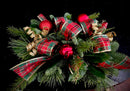 Holiday centerpiece with mixed seasonal greenery, festive embellishments and ribbon loops.