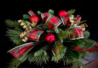 Holiday centerpiece with mixed seasonal greenery, festive embellishments and ribbon loops.