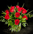 A dozen roses in a shorter, fuller arranged with a premium vase and greenery.