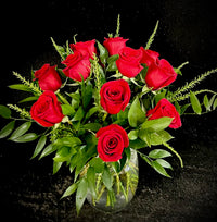 A dozen roses in a shorter, fuller arranged with a premium vase and greenery.