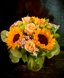 Roses and sunflowers with seasonal filler, accent flowers mixed greenery arranged in a vase. 