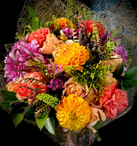 A wrapped mixed floral bouquet In sunset hues.