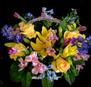 Basket of yellow roses, yellow asiatic lilies with pink and purple accent blooms, and mixed greens.