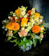 Festive Halloween themed arrangement in a ceramic skulll printed vase.